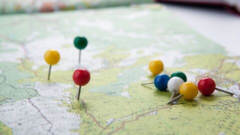 Stecknadeln in einer Landkarte Gelbe, grüne und rote Stecknadeln stecken in einer auf dem Tisch liegenden grünen und weißen Landkarte aus Papier, die einen Flächennutzungsplan darstellt.